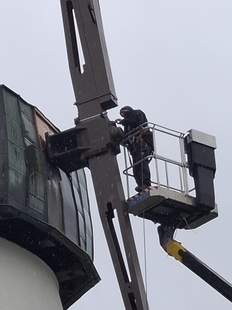 A craftsman installs the sails at the top of the mill