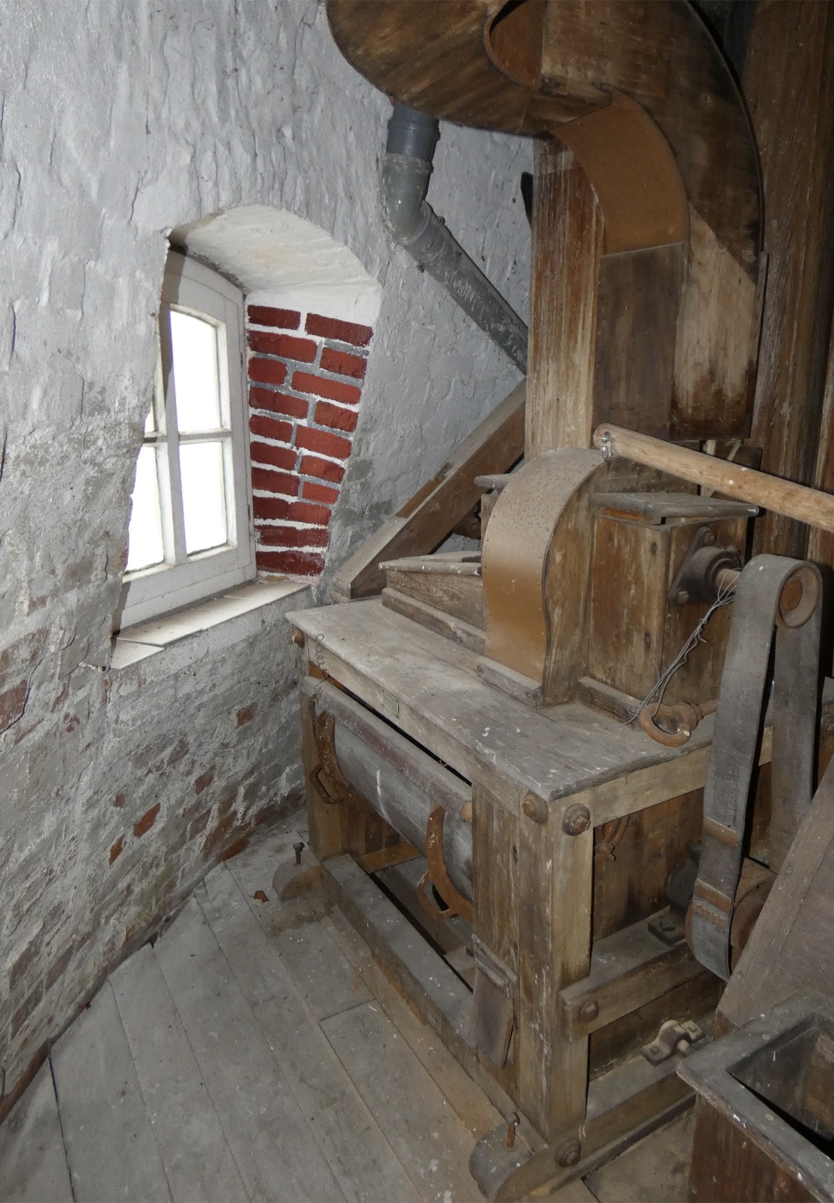 Maquinaria histórica de madera junto al muro de ladrillo